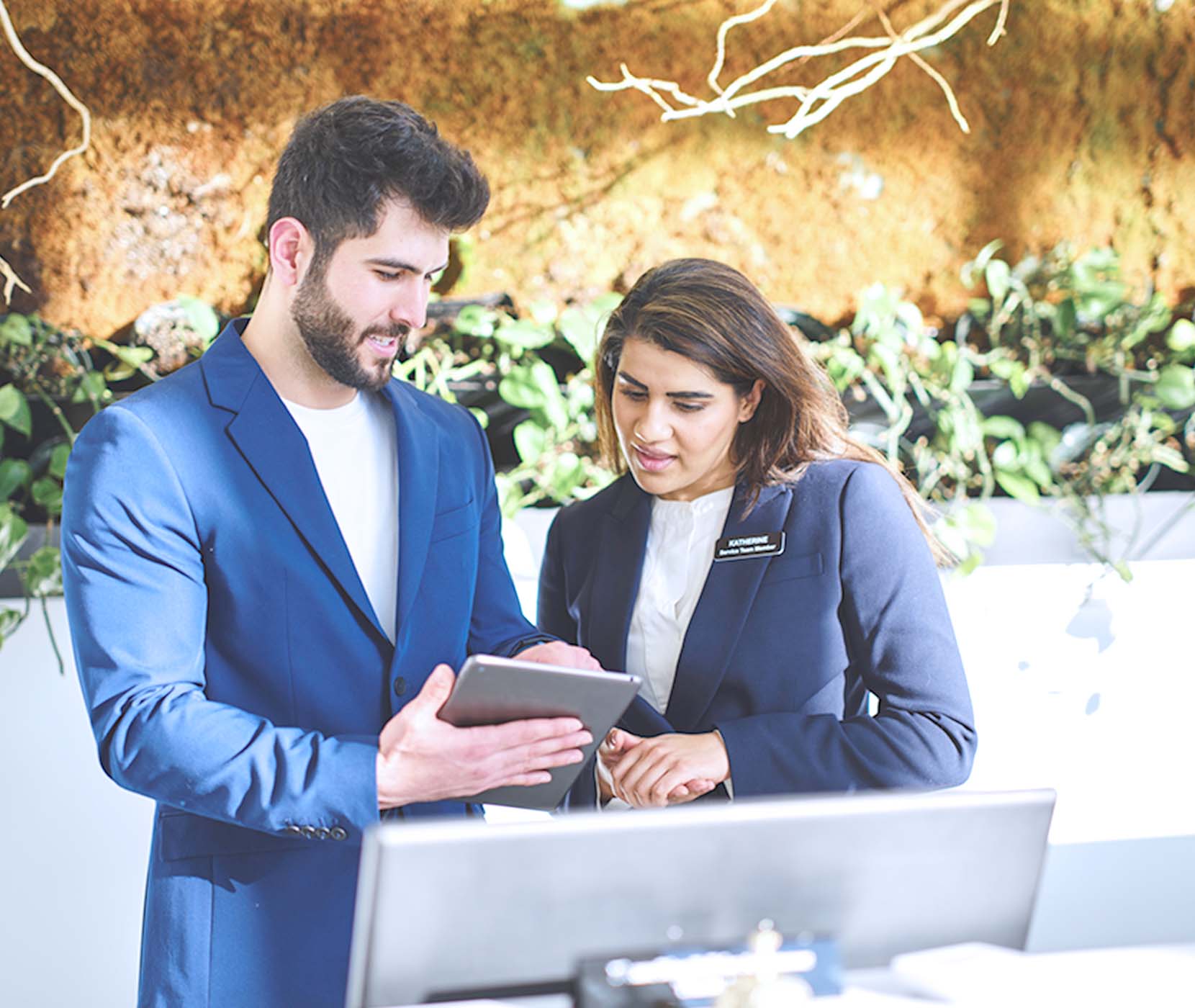 Hotel managers looking at a tablet at the front desk.