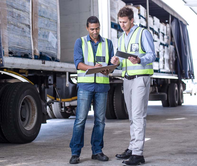 Two males wearing safety vests looking at a tablet