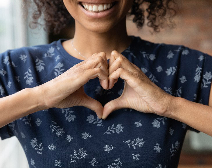 Smiling biracial woman show heart hand gesture