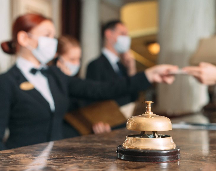 Check in hotel. receptionist at counter in hotel wearing medical masks as precaution against virus. Young woman on a business trip doing check-in at the hotel