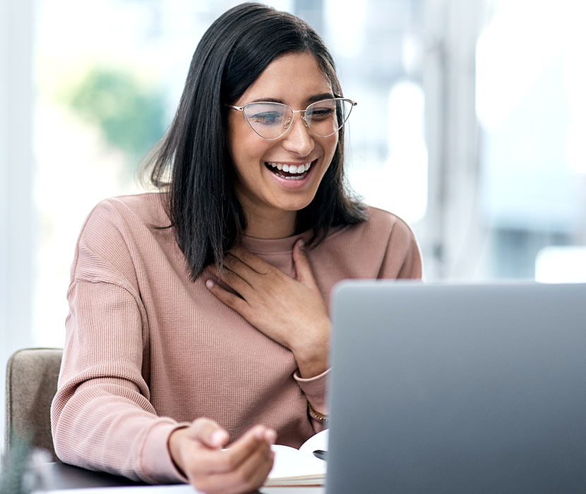 A female smiling in the office looking at a laptop.