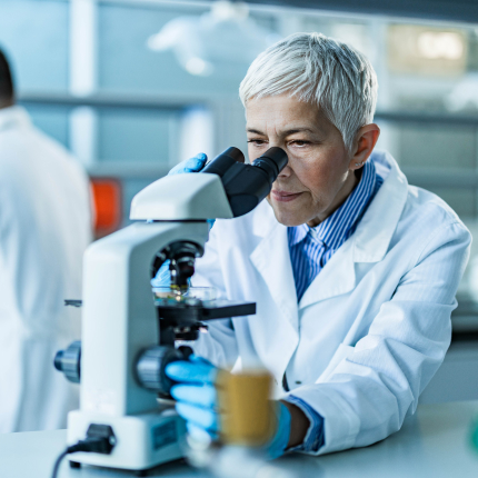 A lab tech looking into a microscope.
