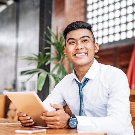 A smiling male in an office holding a tablet.