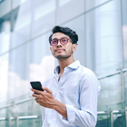 A man holding a smartphone looking out into the distance.