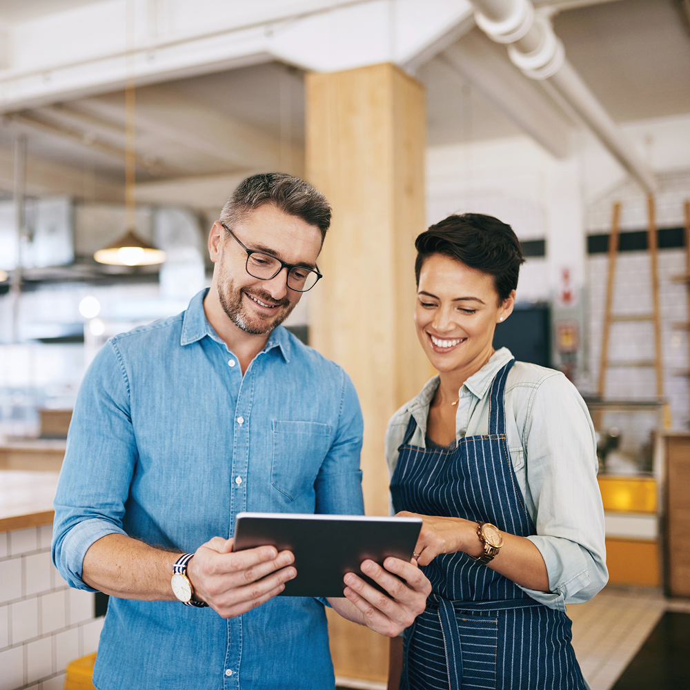 Two small business owners reviewing a background check on a tablet